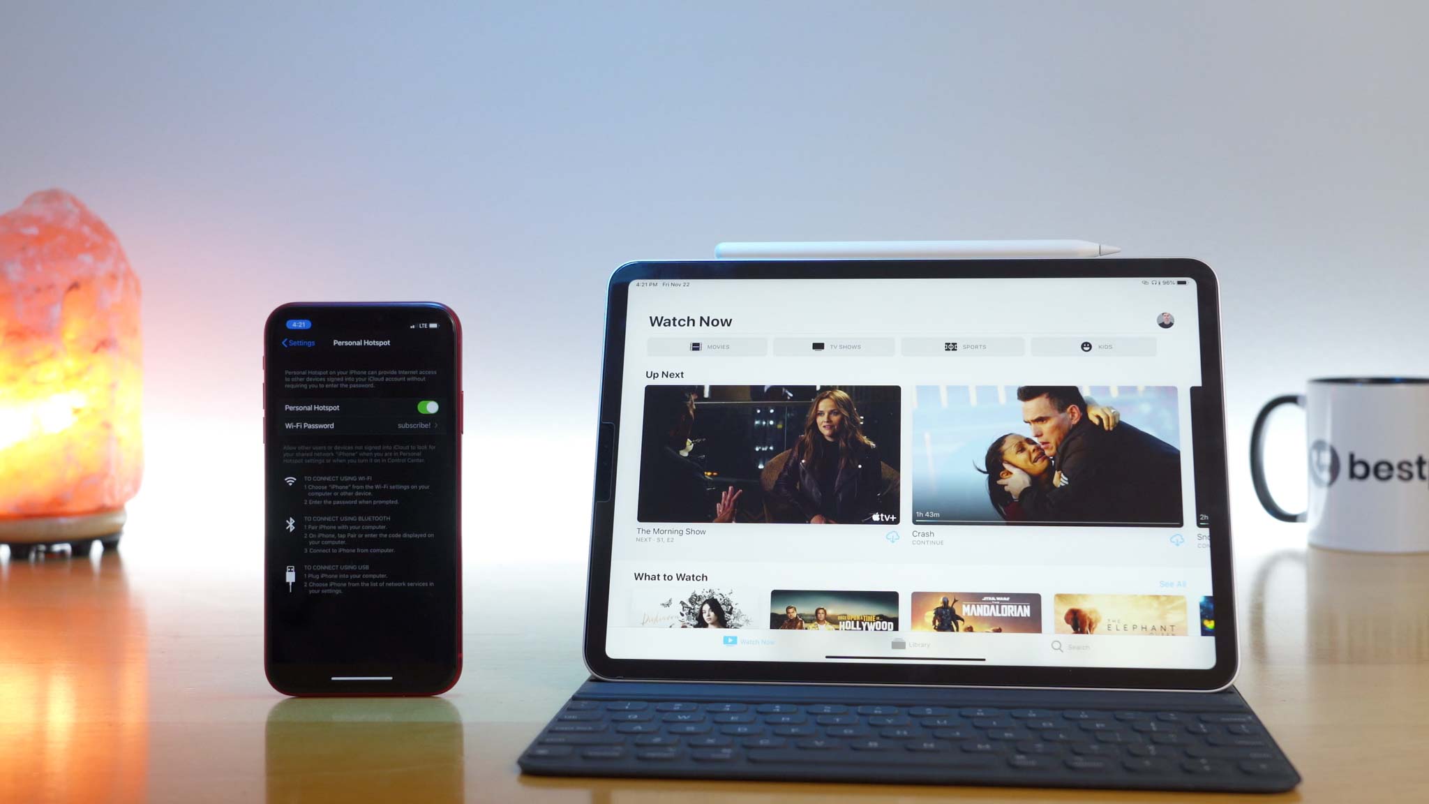 iPhone 11 Pro with hotspot enabled sharing cellular data with iPad Pro next to it open to the Apple TV app