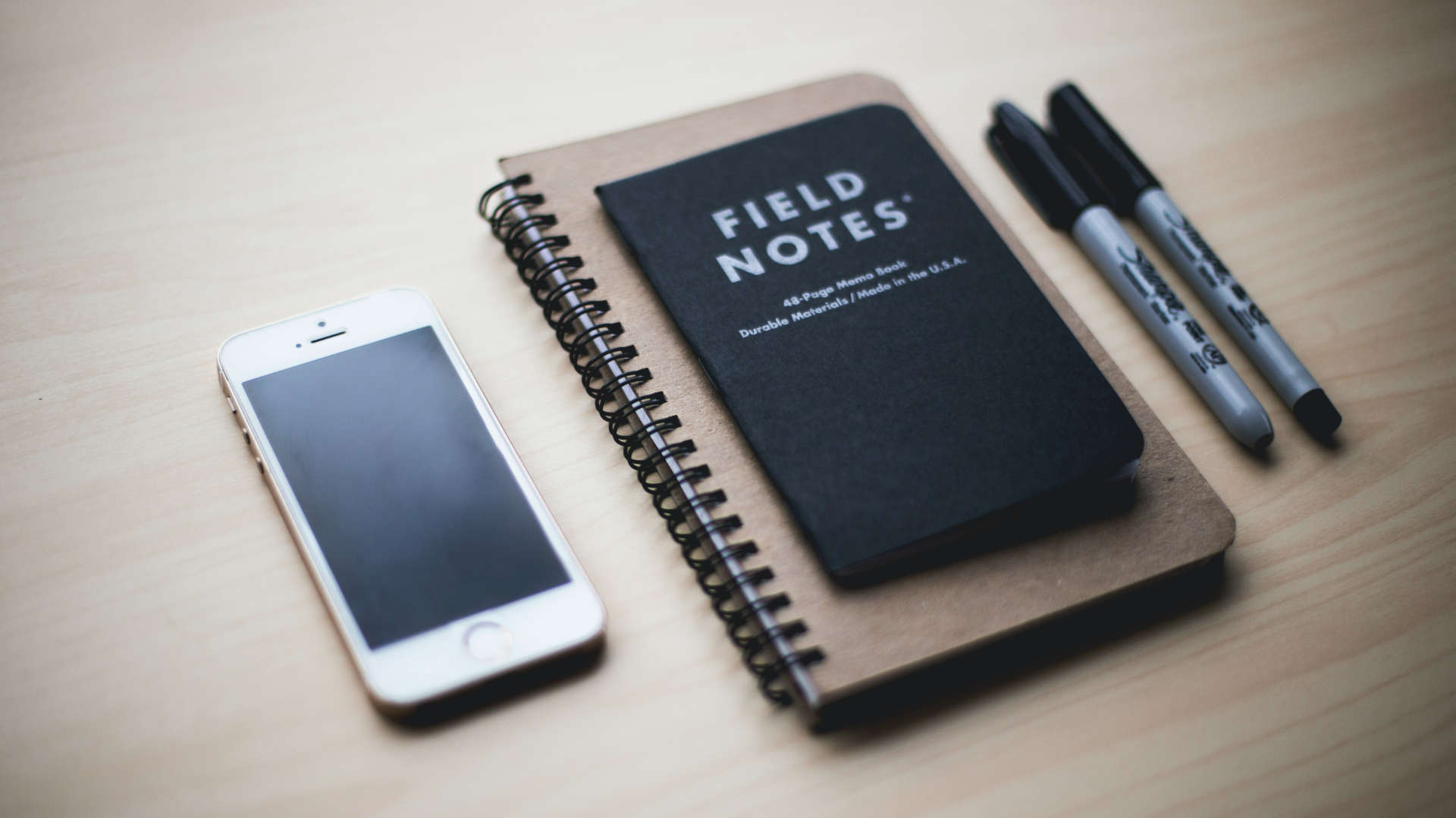 cell phone next to notebook and pen on desk