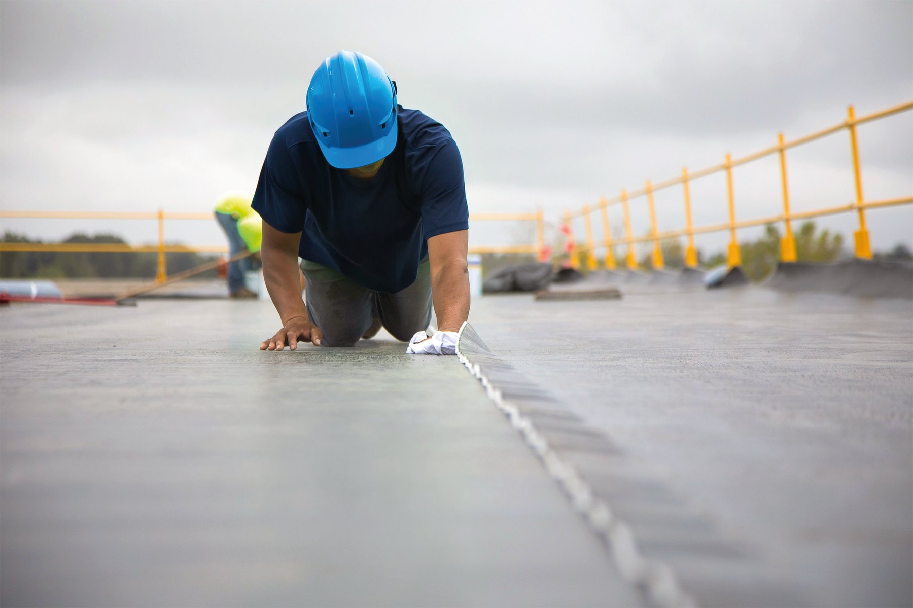 Dakdekker drukt de naad van Roof EPDM Fix Pretaped aan op een plat dak