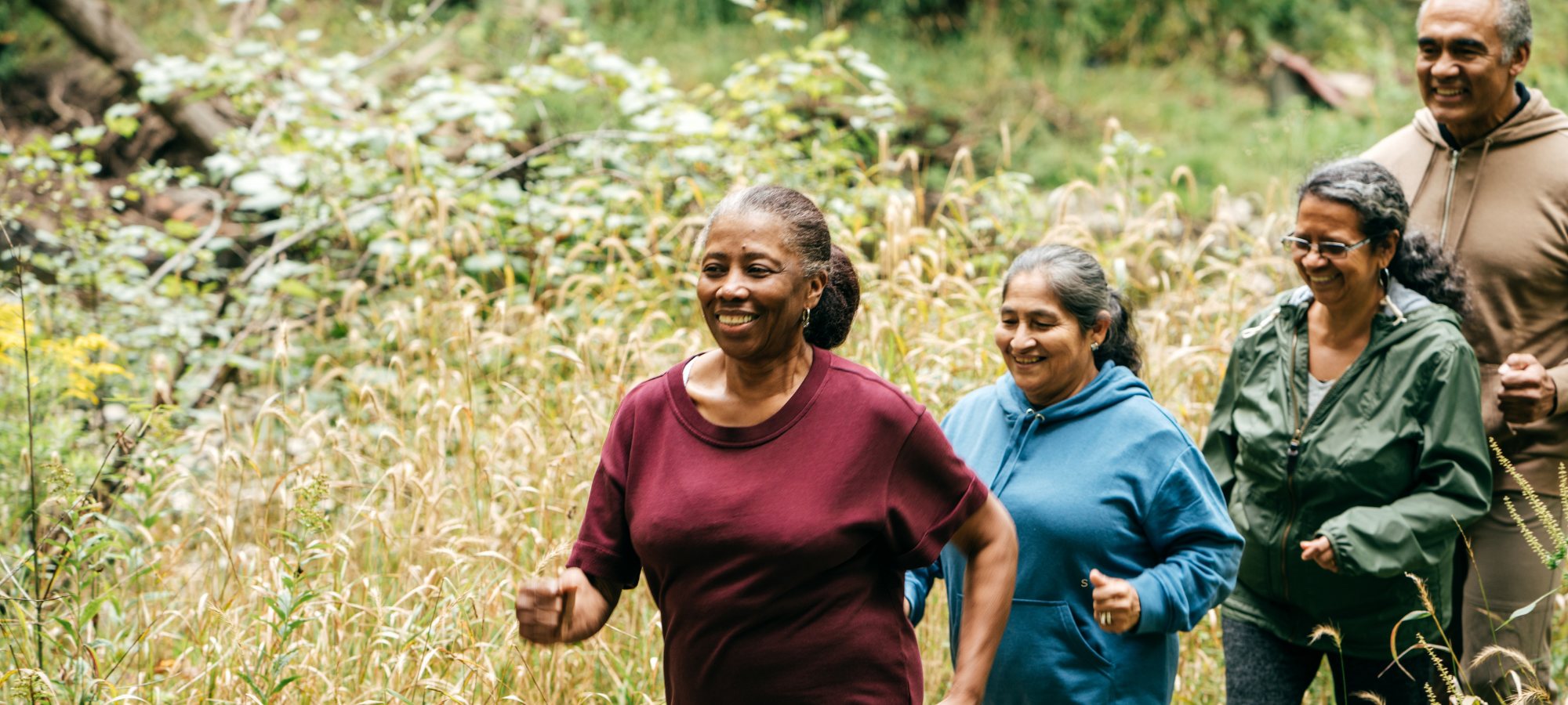 Four people smiling, walking in nature