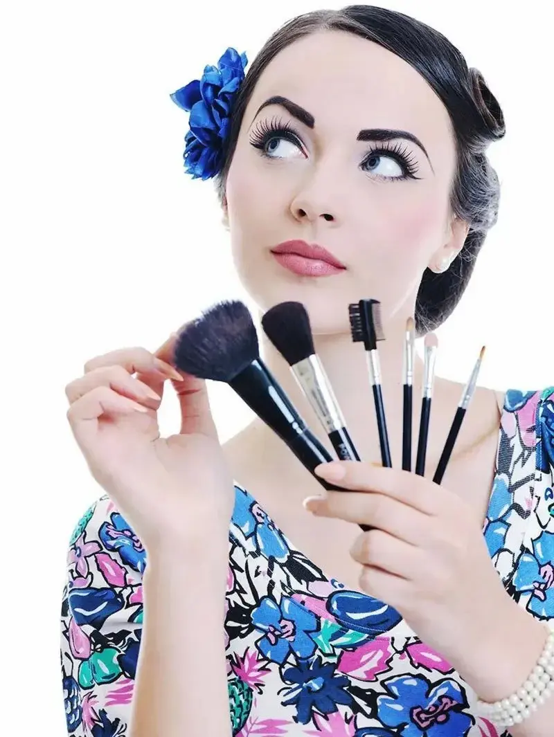 A woman looks up thoughtfully, holding a brush, symbolizing artistic expression and contemplation.