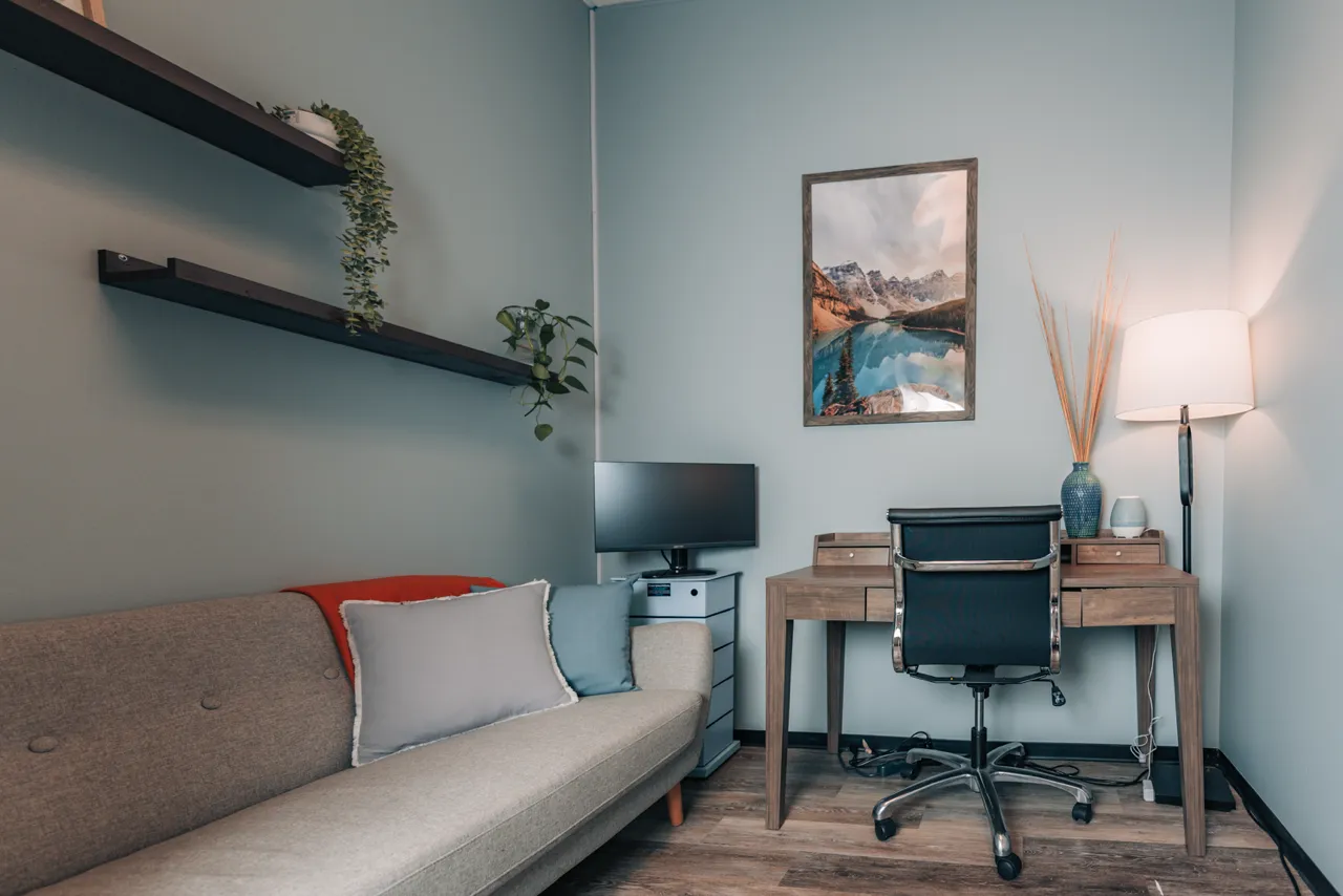 A living room with a couch and a desk.