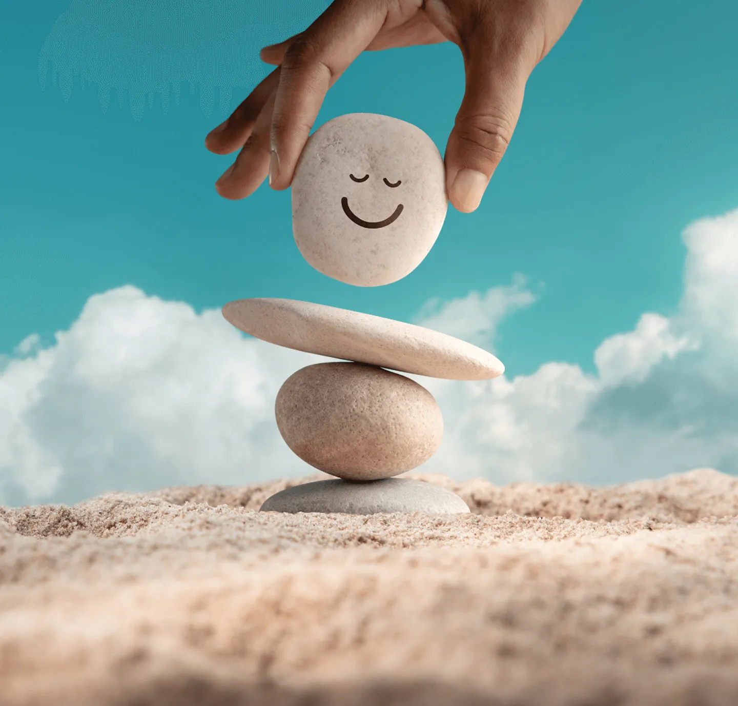 A hand is placing a rock on a stack of rocks.