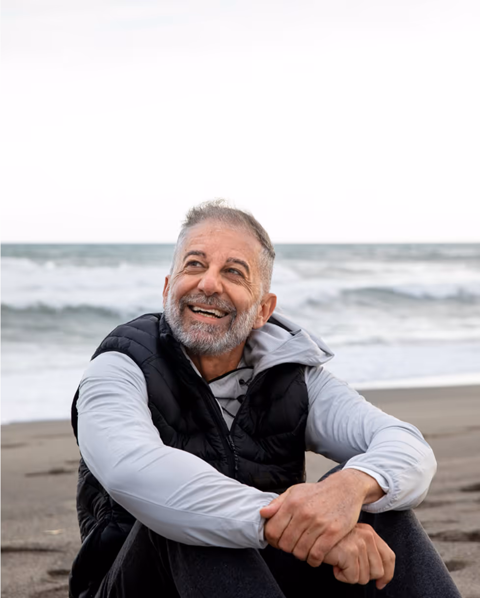 A man with a gray beard and mustache is smiling.