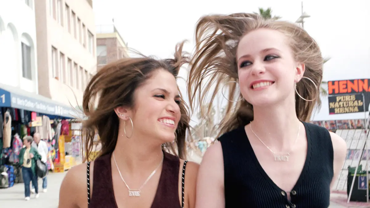 Movie still from Thirteen. Two teen girls smile on a boardwalk in California, giddy