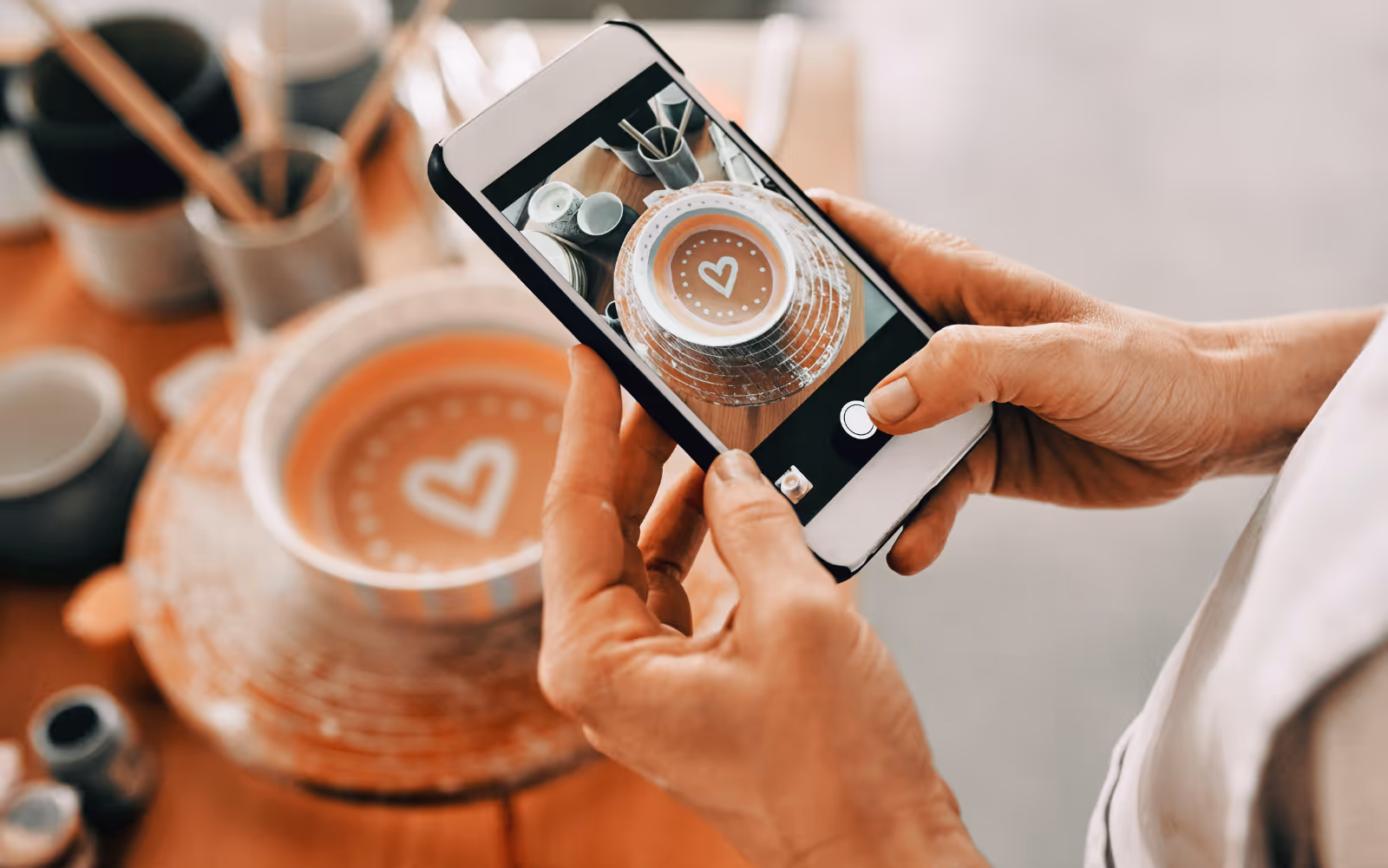 A person takes a photo on their mobile phone of a piece of ceramic they have created. 