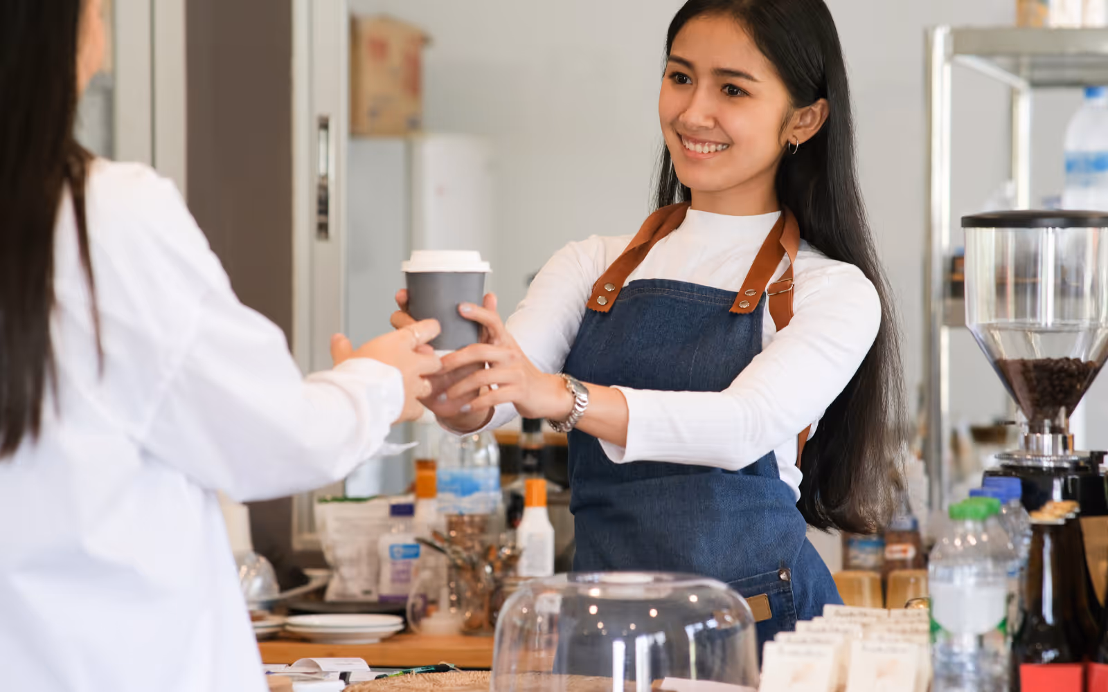 Barista handing a freshly brewed coffee to a customer, showcasing excellent customer service at a cafe