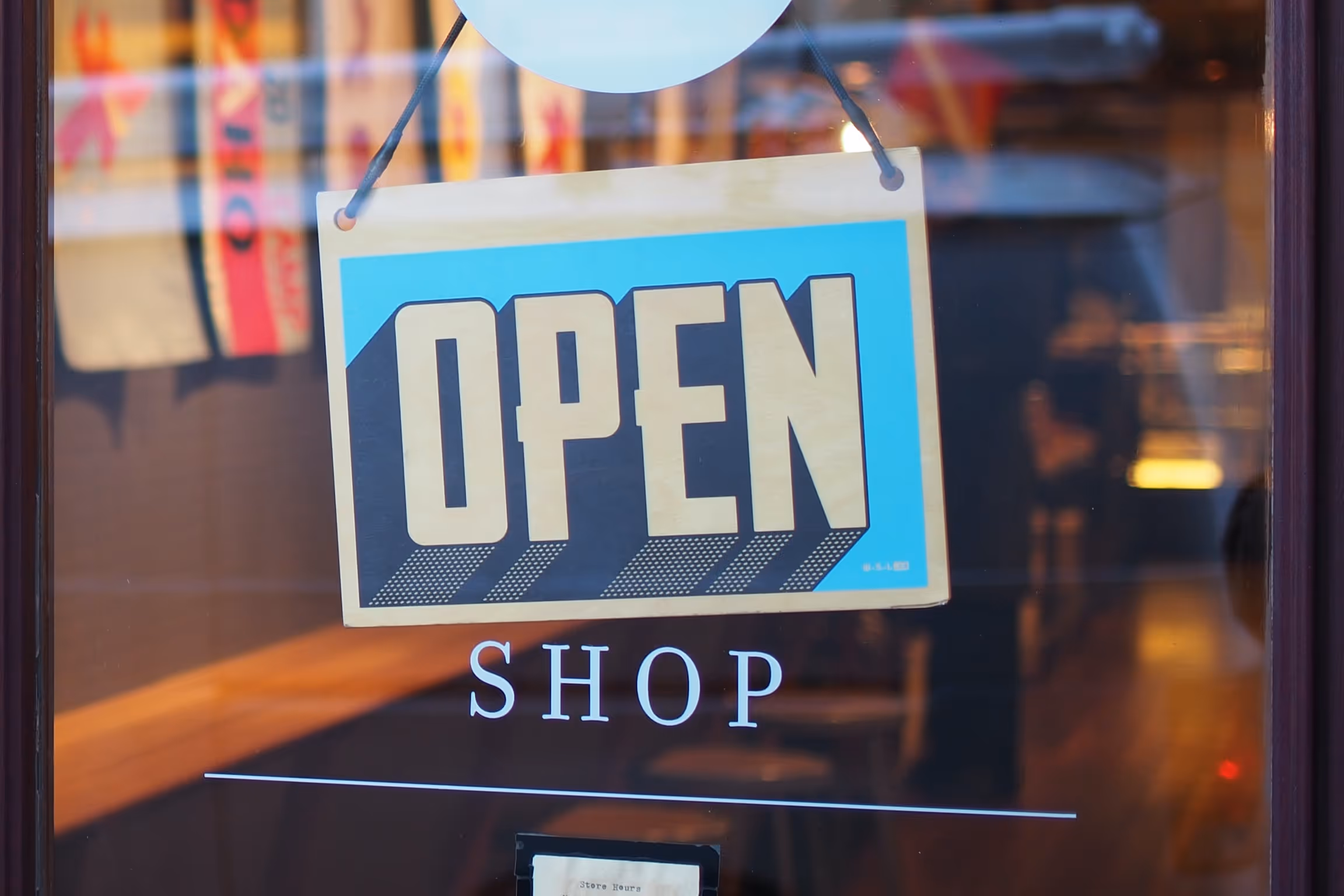 Open sign hanging over a car wash window, indicating business hours and welcoming customers.