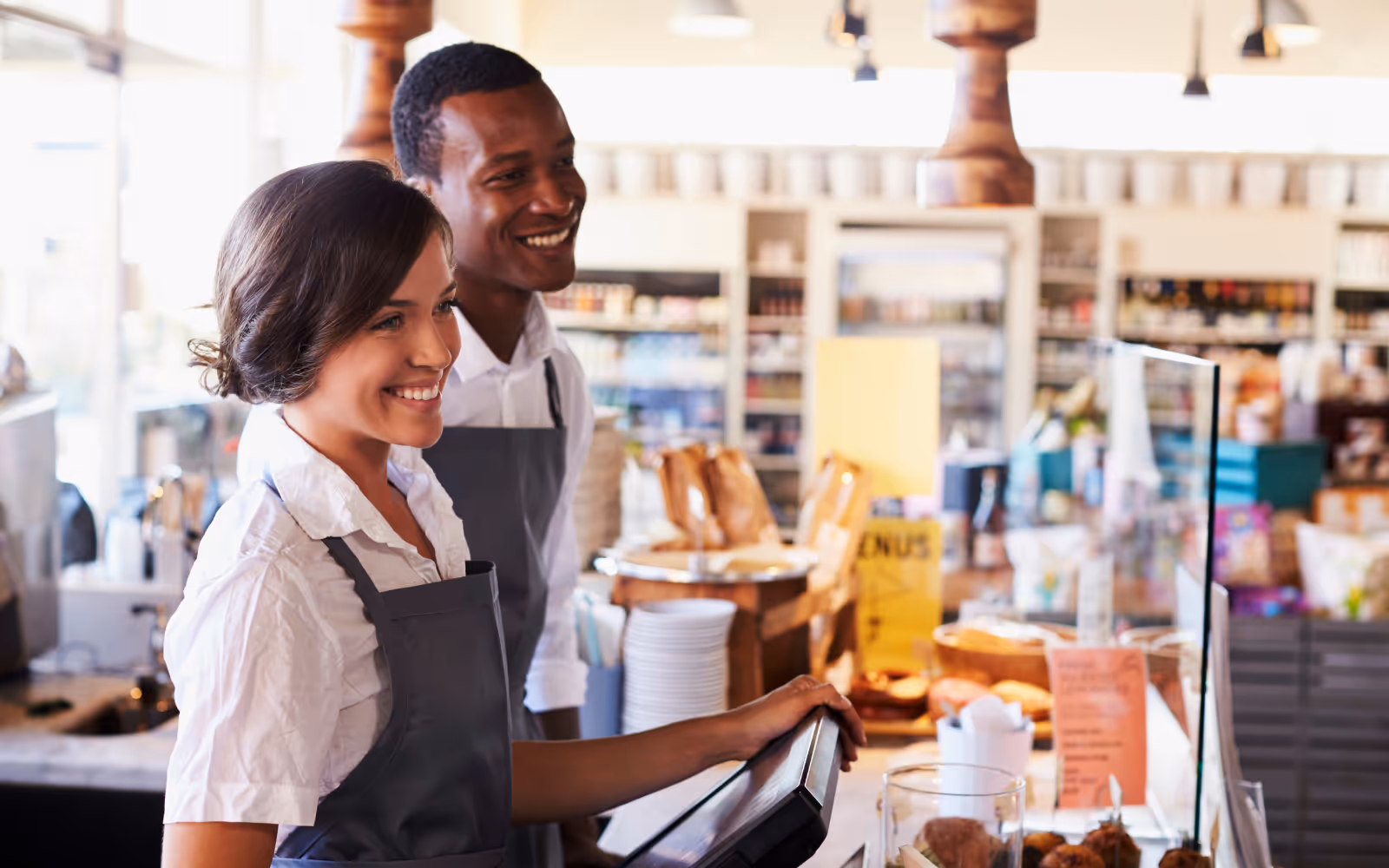 Staff members smiling in a cafe at a customer. 