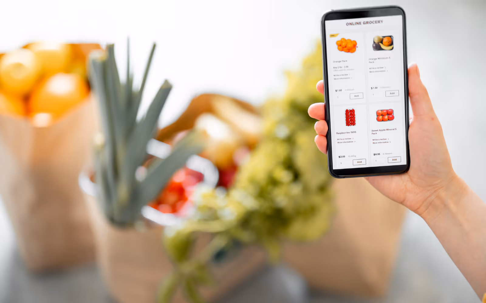 Hand holding a phone with various grocery items. 