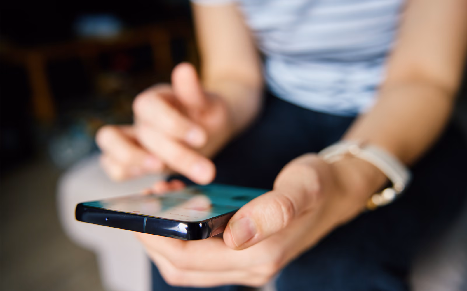 Zoom in of someone's hands as they scroll on their phone. 