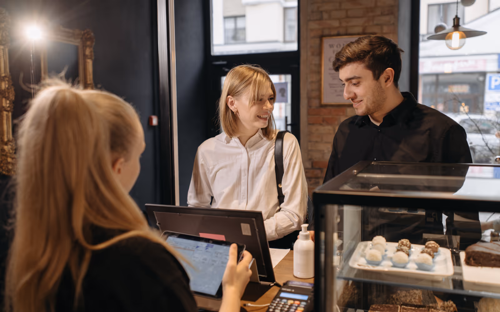 Two people smiling in front of a cafe's POS