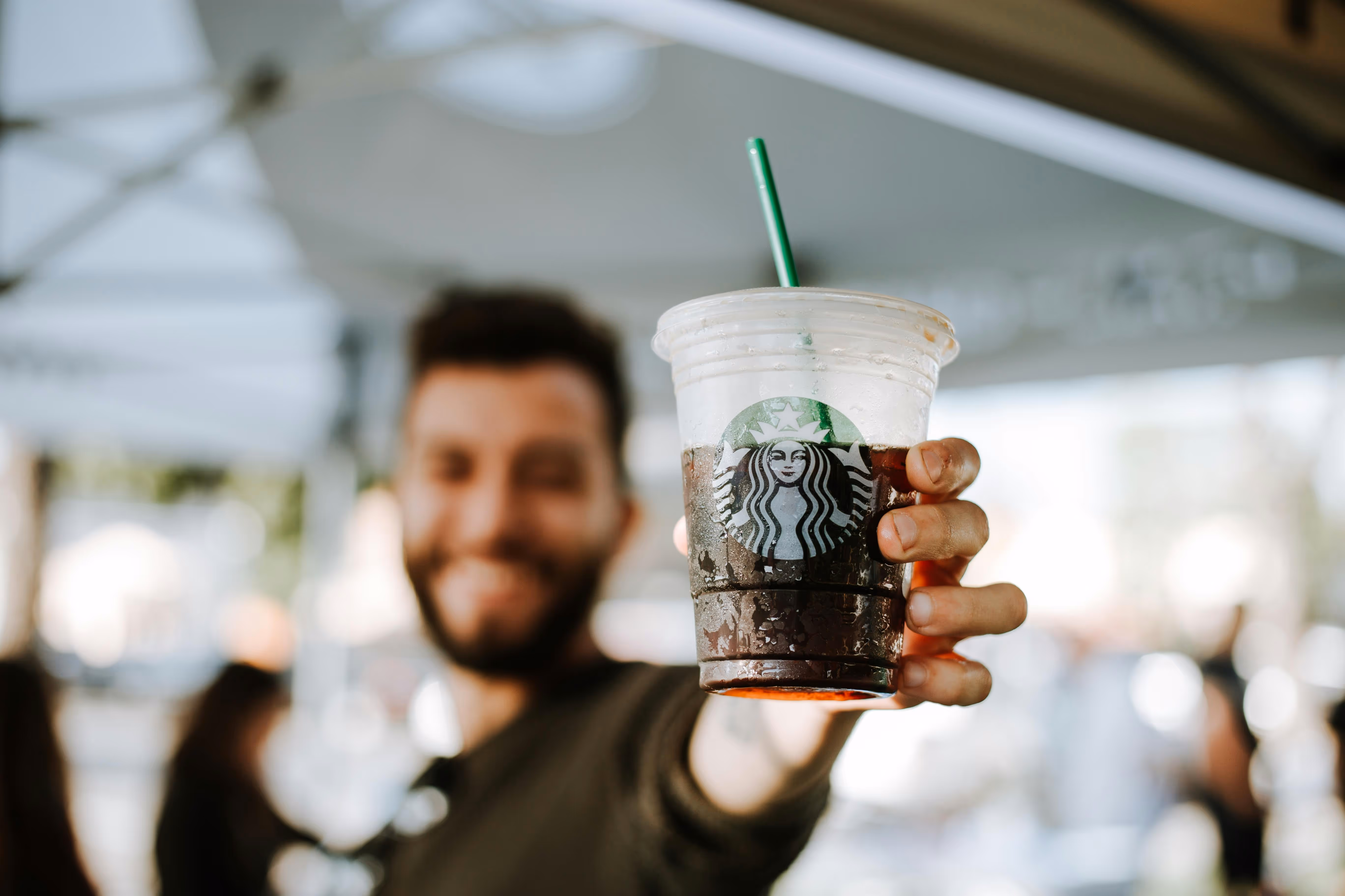 Person smiling and holding a Starbucks cup.