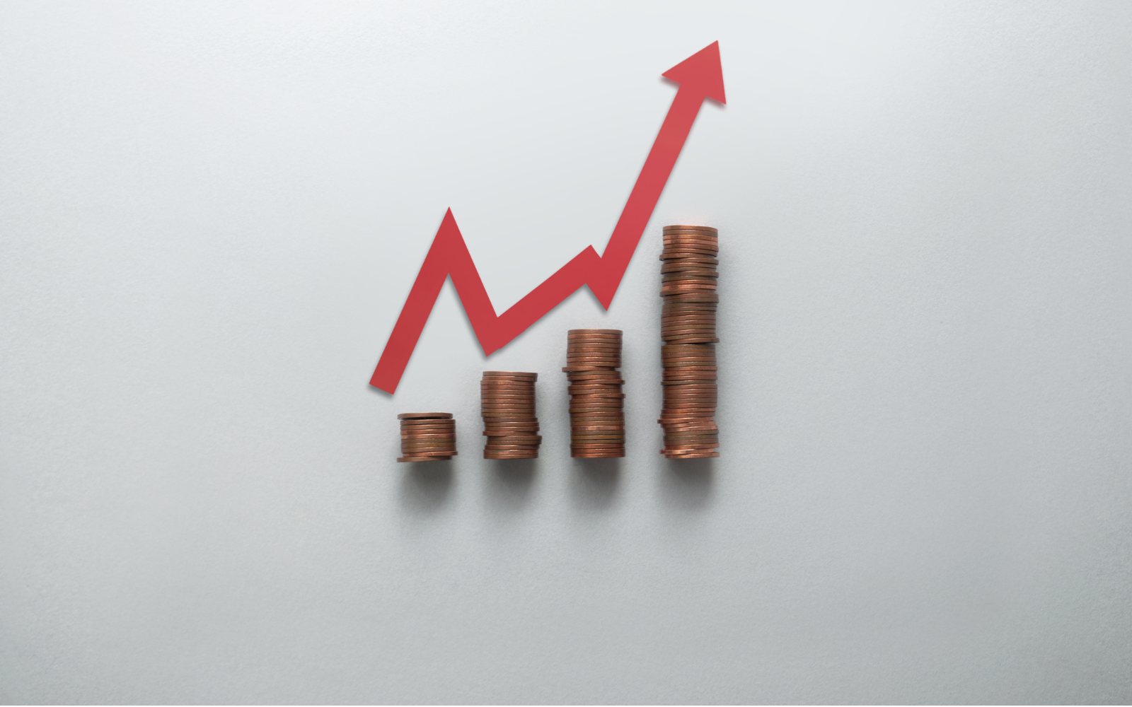 Stacked coins with an upward arrow representing loyalty app pricing tiers for UK small businesses.