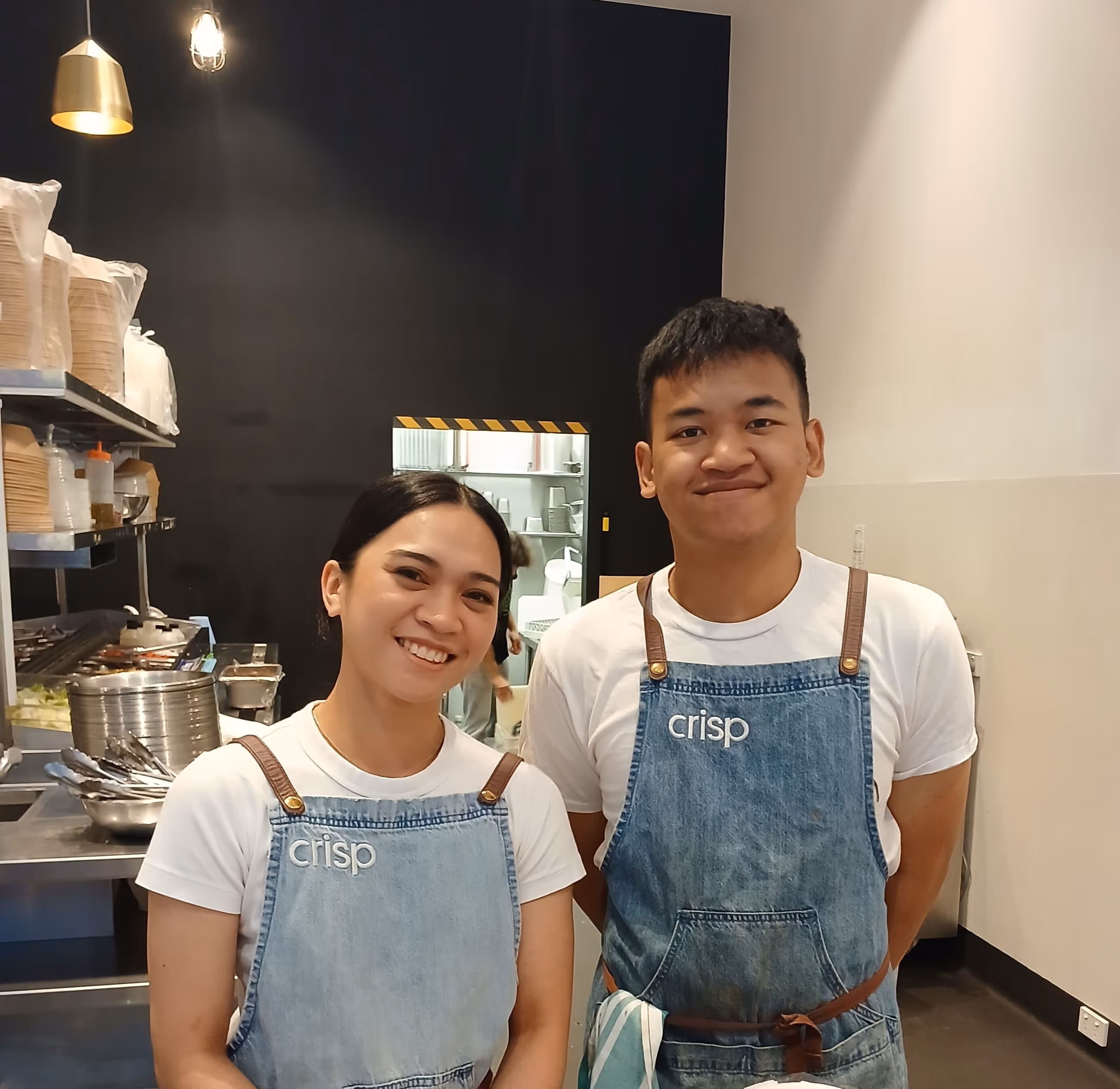 Friendly staff at Crisp Creative Salad preparing healthy meals and providing excellent customer service.