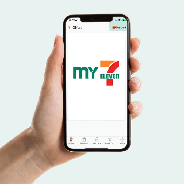 Hand holding a smartphone displaying the My 7-Eleven Rewards app in Australia