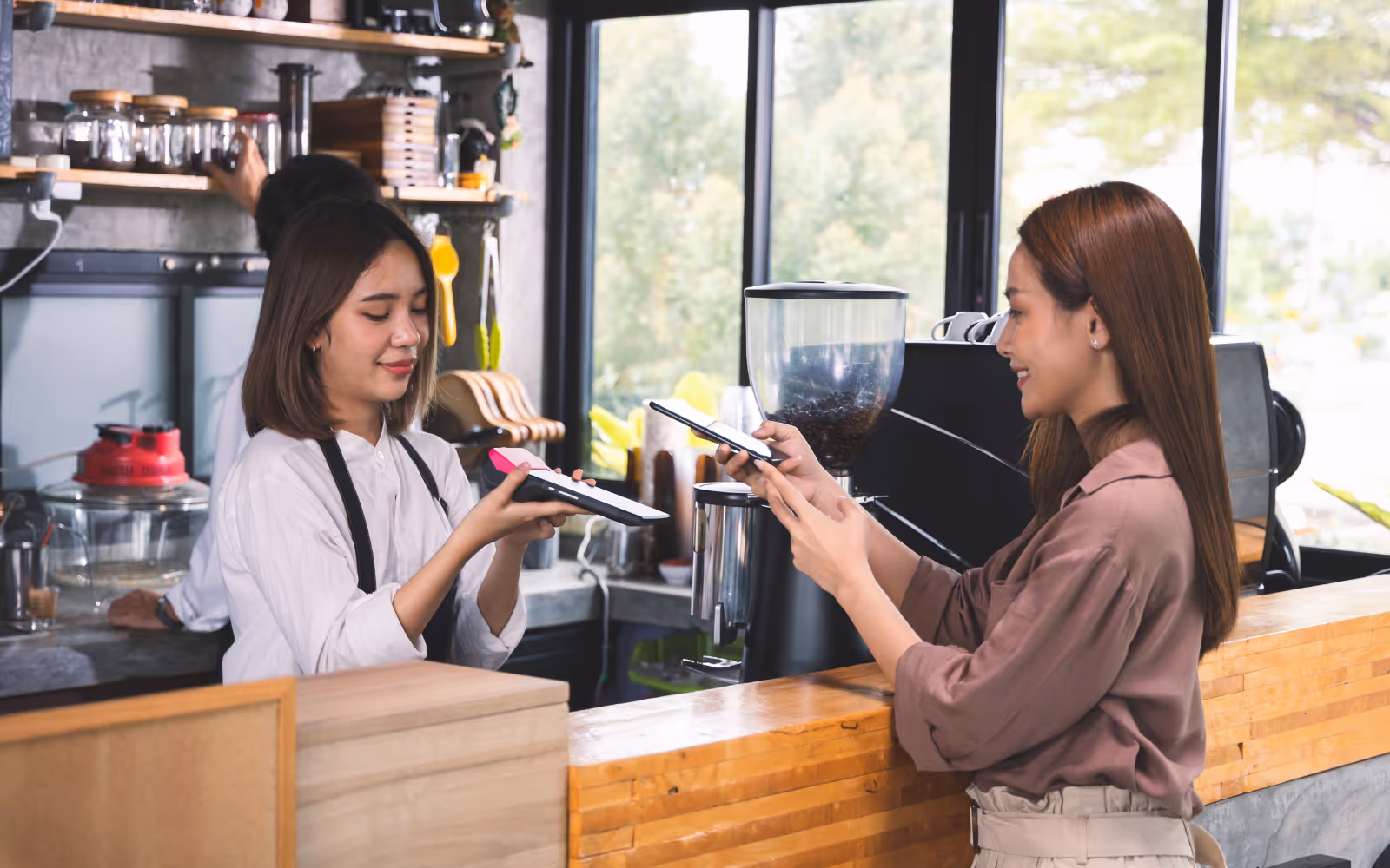 Smiling customer paying at a café counter, showing how simple loyalty programs increase repeat purchases and customer retention