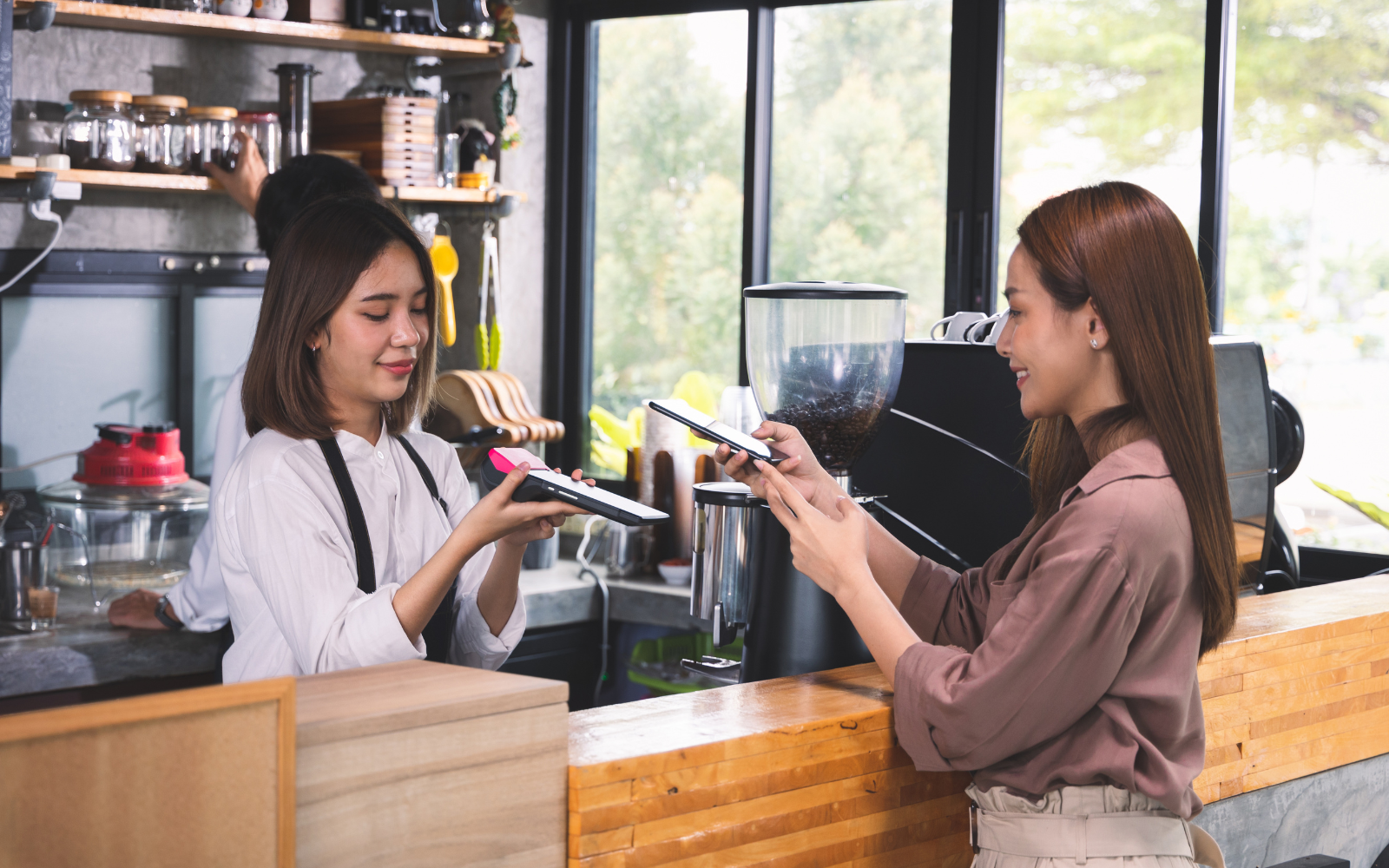 Smiling customer paying at a café counter, showing how simple loyalty programs increase repeat purchases and customer retention