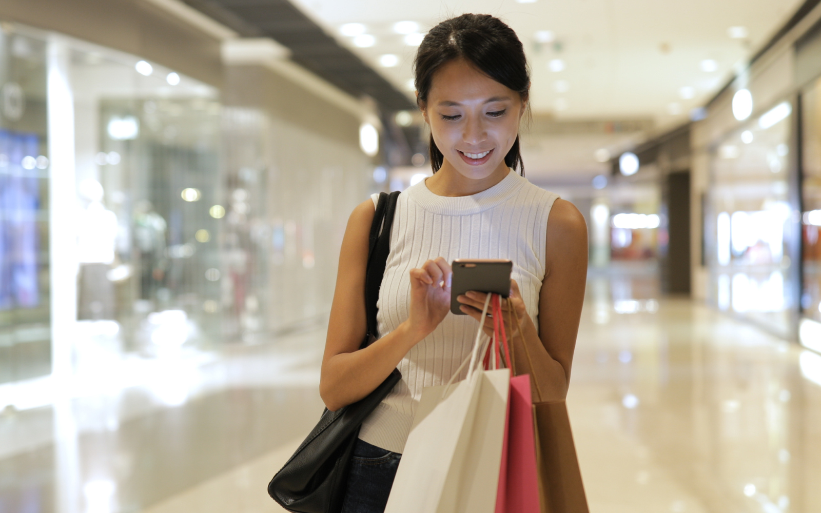 Shopper looking at their phone inside an Australian retail store, symbolising digital loyalty apps and customer engagement.