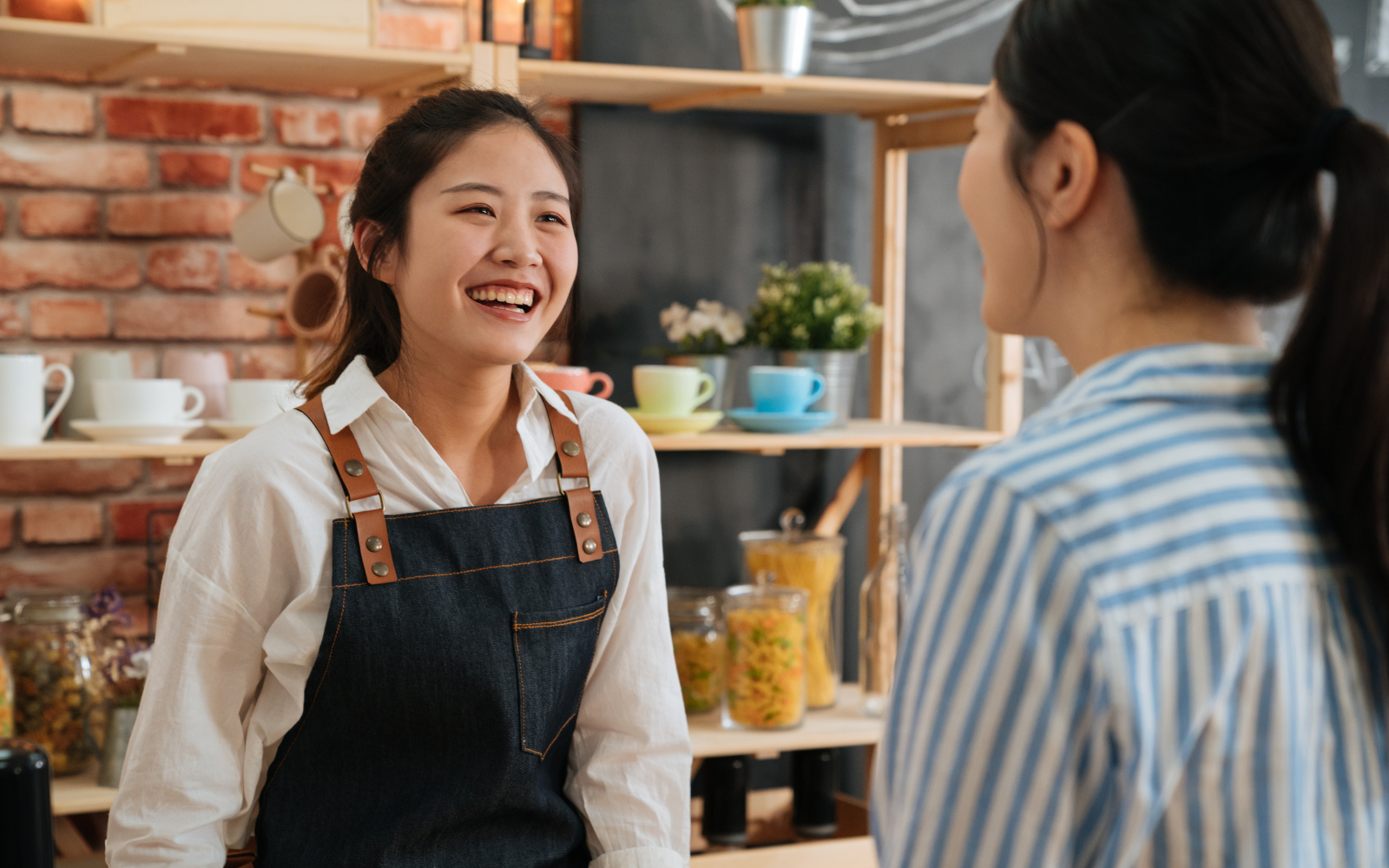 Smiling barista talking to a customer in an Australian cafe, building customer loyalty through personal connection.