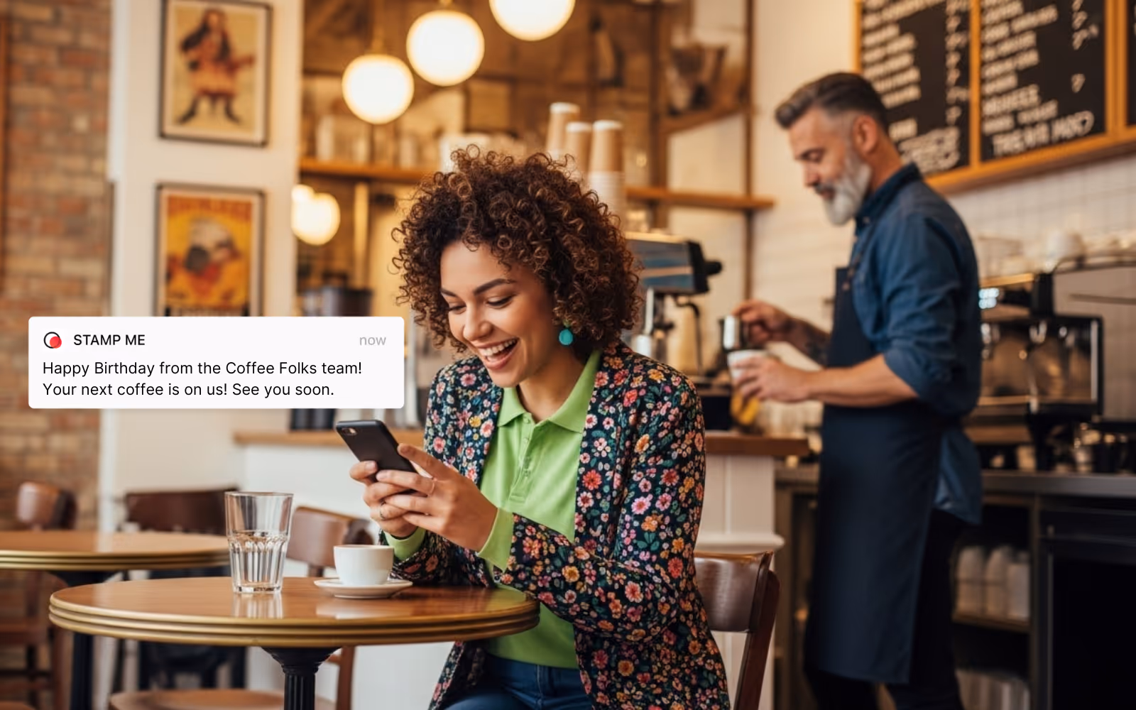 Woman in a coffee shop receiving an automated birthday reward text from a Stamp Me loyalty program, highlighting customer engagement and retention.