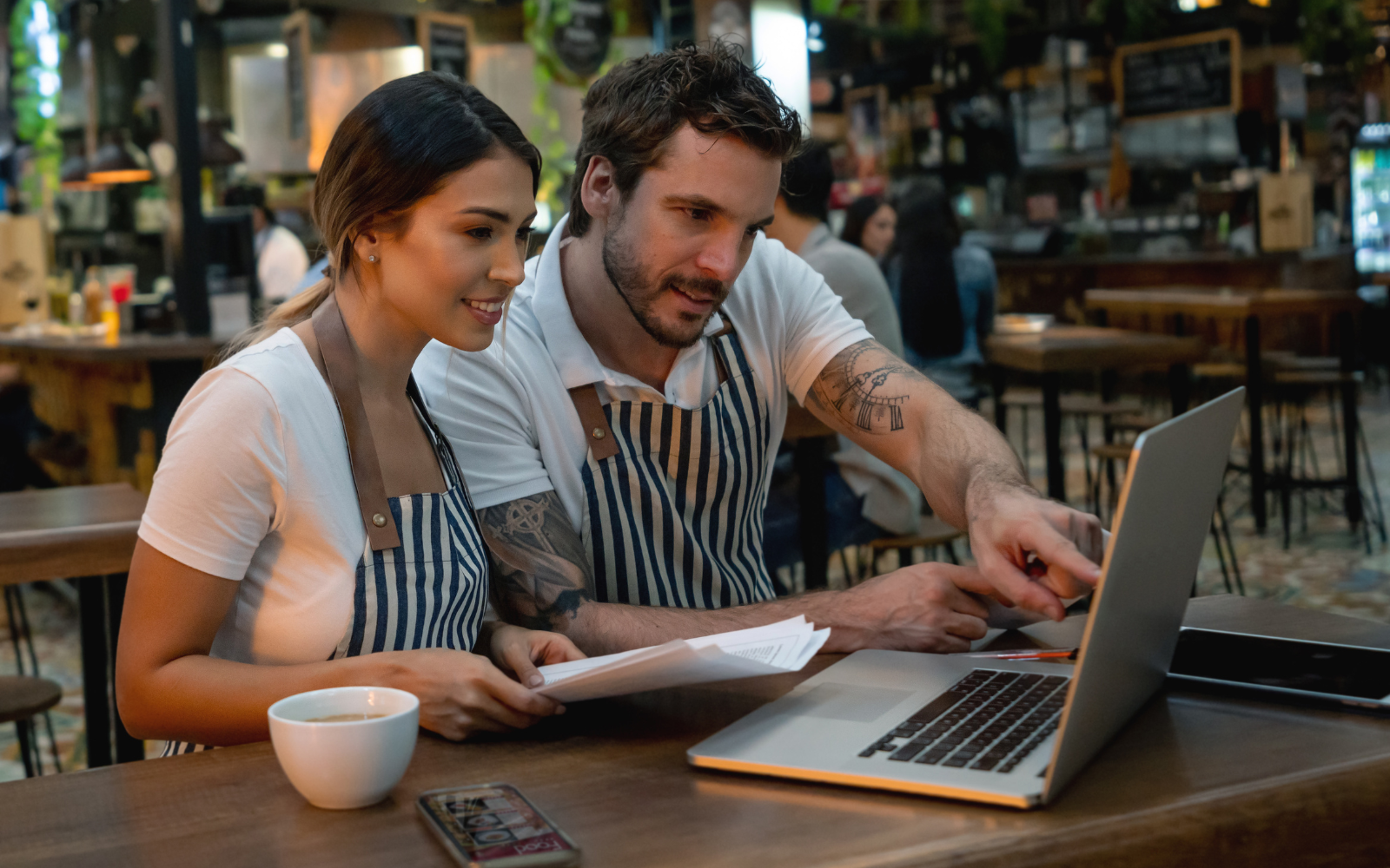Two staff members looking at a computer, after launching their cafe loyalty program.