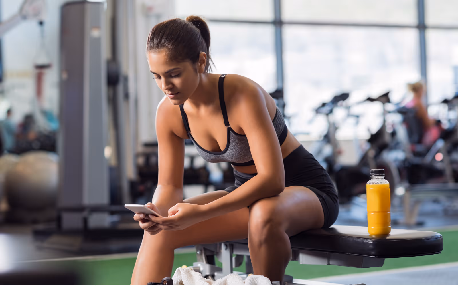 Gym goer on their mobile phone, taking a break from their workout. 