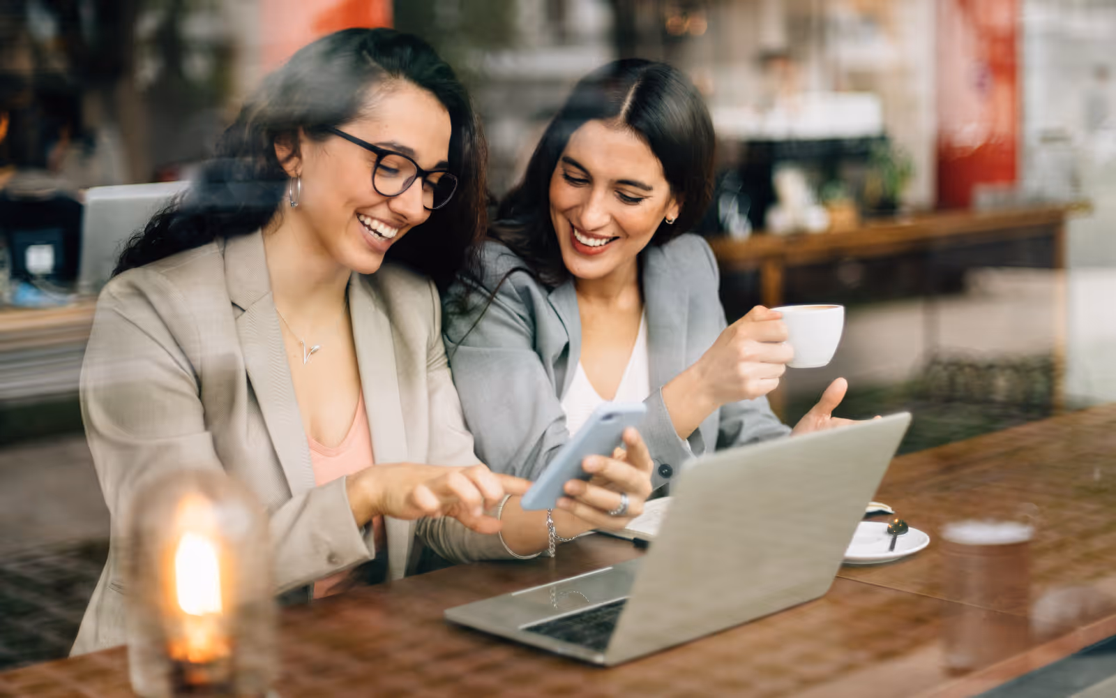 Coffee shop customer sharing digital loyalty program rewards with a friend, driving referrals