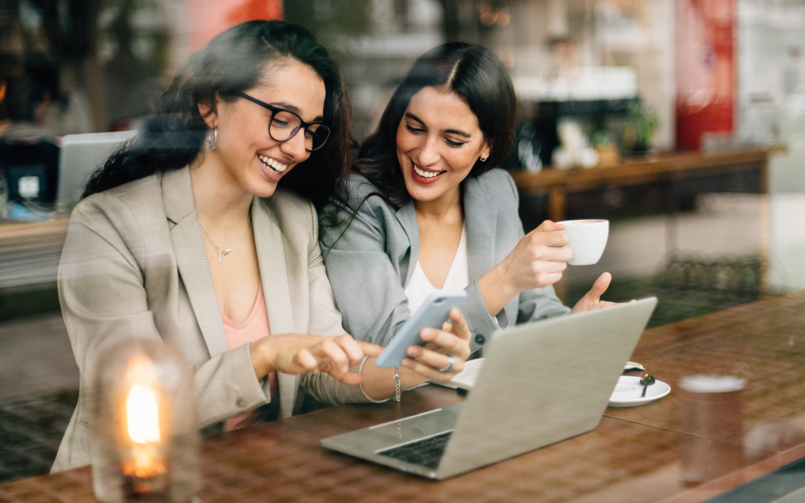 Coffee shop customer sharing digital loyalty program rewards with a friend, driving referrals