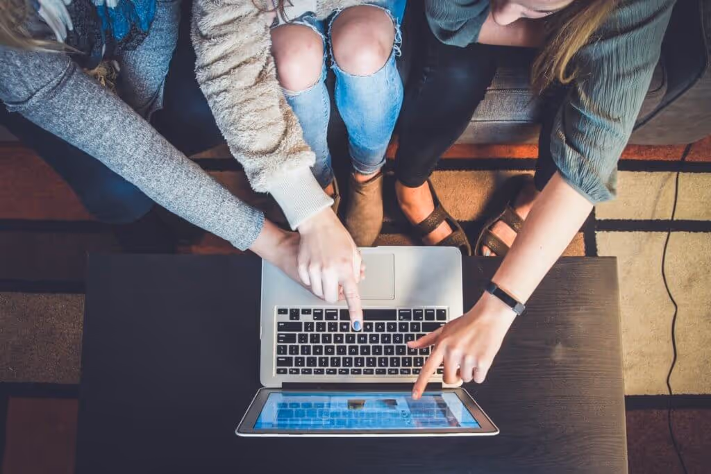 3 people looking and pointing at a laptop screen