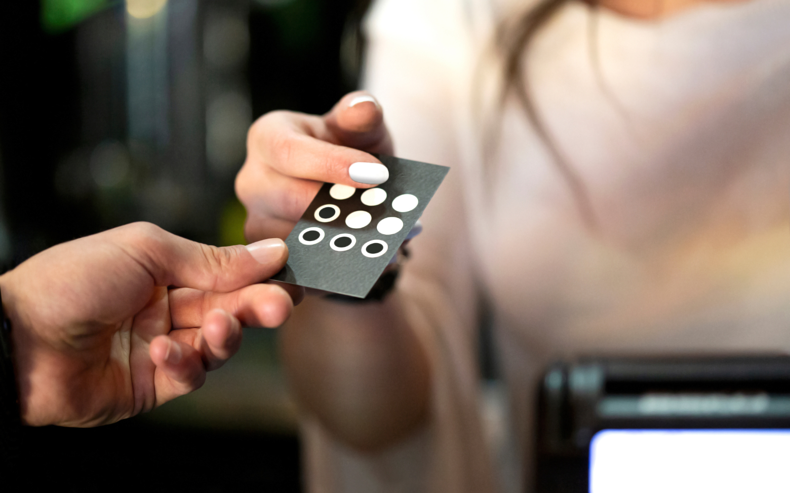 Paper punch card being passed from worker to customer.