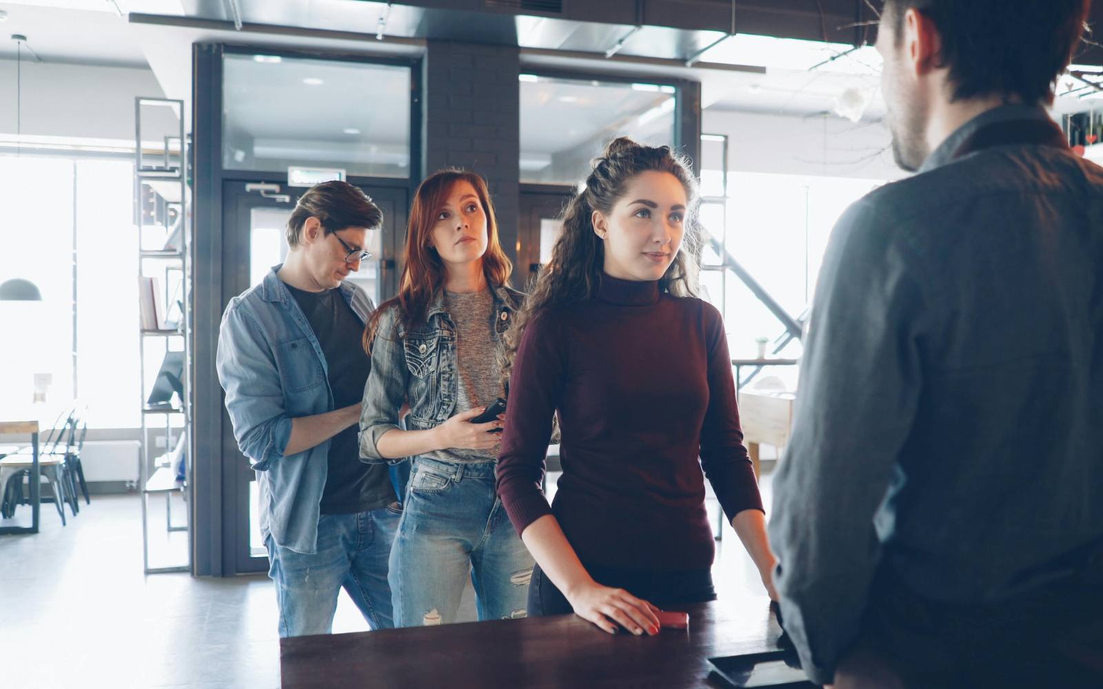Barista warmly welcoming a returning regular customer at an Australian cafe counter — building loyalty through personal recognition