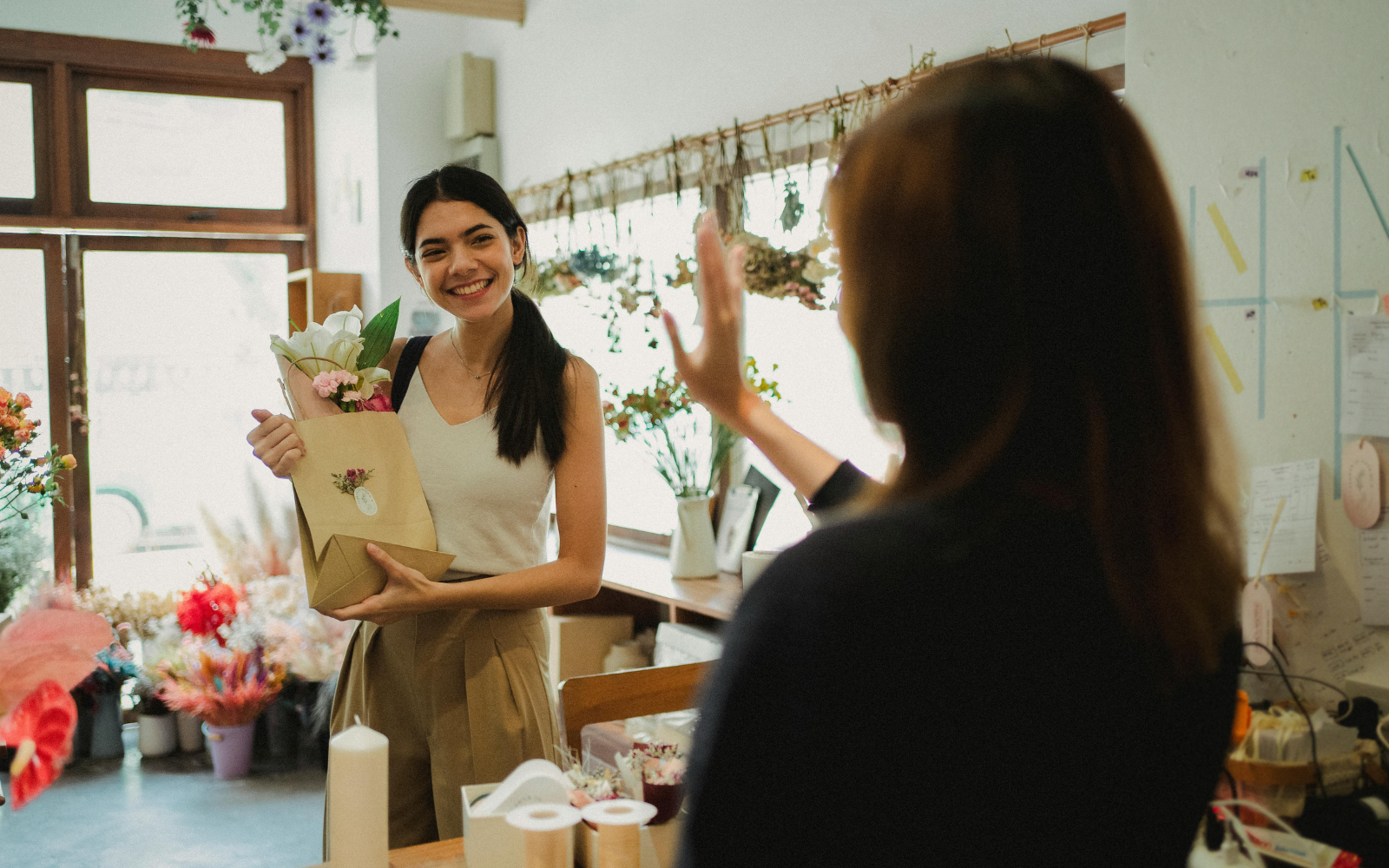 Independent shop owner warmly greeting a returning customer inside a boutique or cafe.