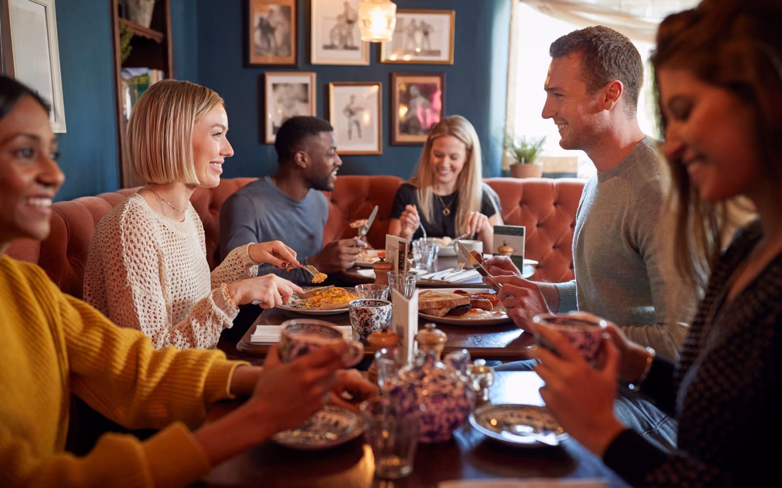 Restaurant server scanning a customer's phone to add a digital loyalty stamp, showing a contactless restaurant loyalty app in use