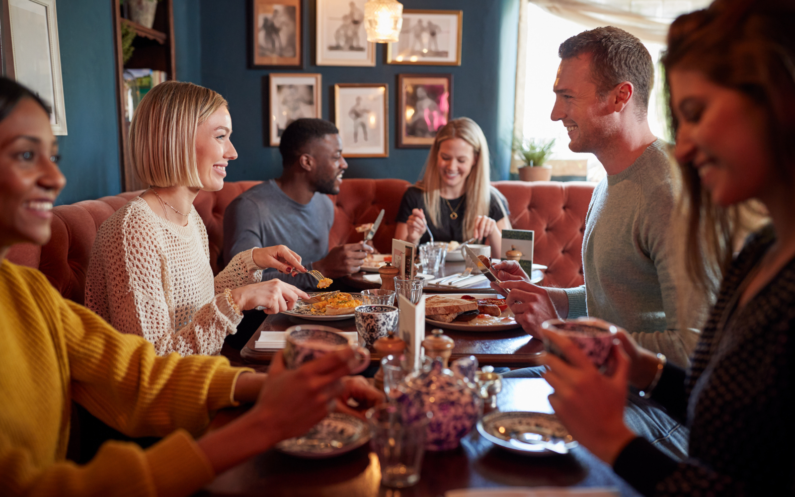 Restaurant server scanning a customer's phone to add a digital loyalty stamp, showing a contactless restaurant loyalty app in use