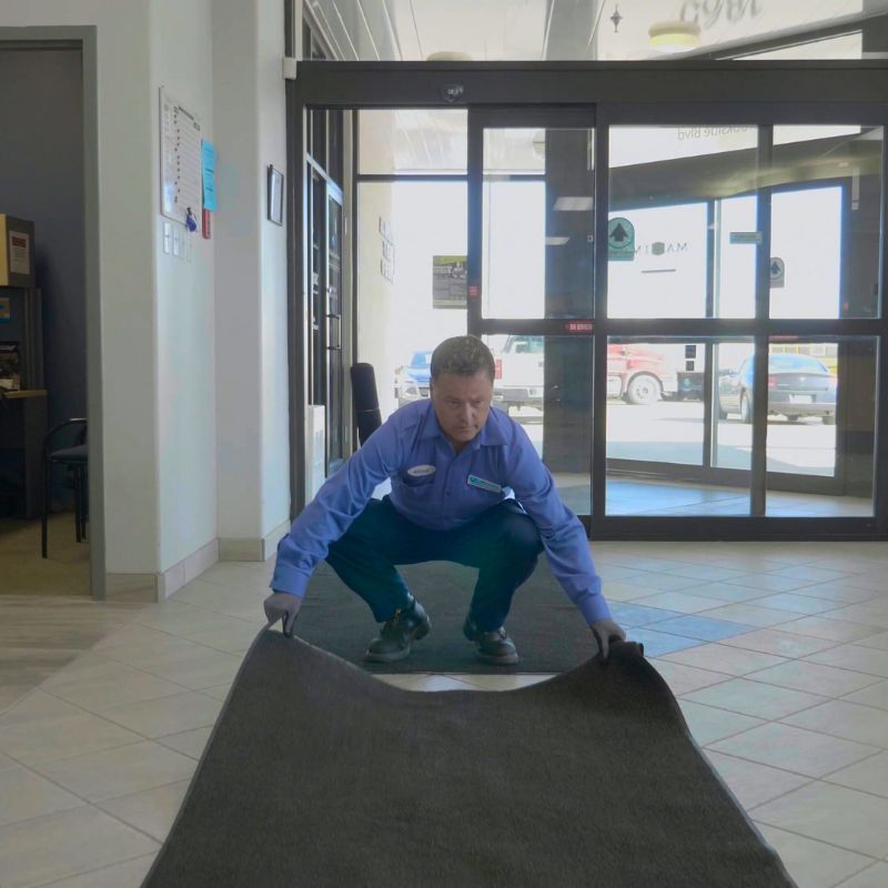 district manager placing a mat down at the front entrance of a facility