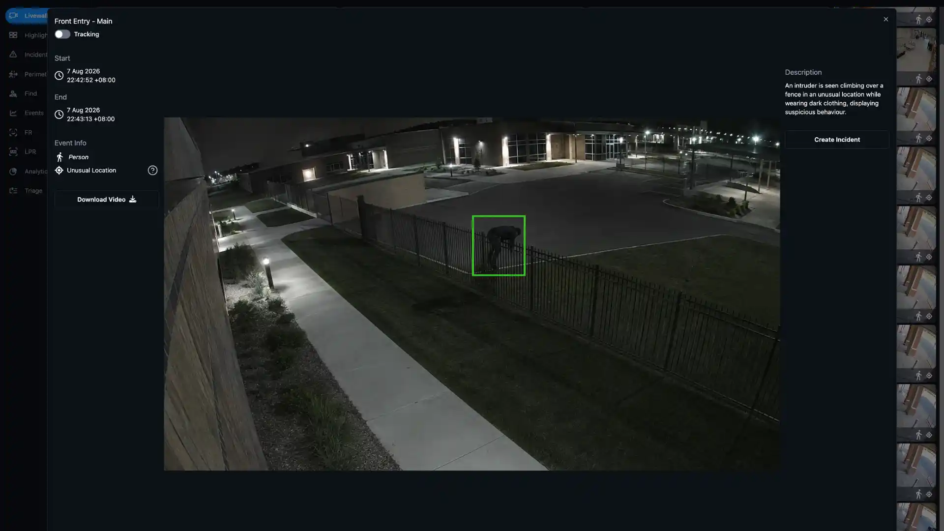 Person dressed in dark clothing climbing over a metal fence at night in a fenced area outside a building.