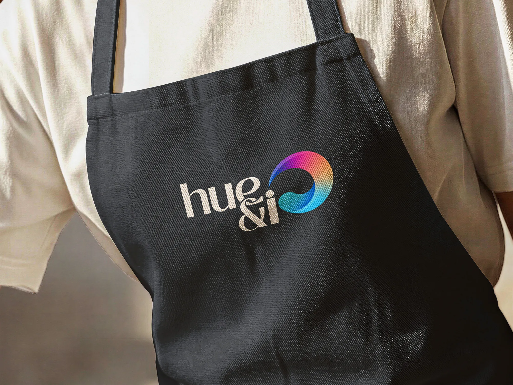 Colourful Hue & I logo embroidered on a black apron.