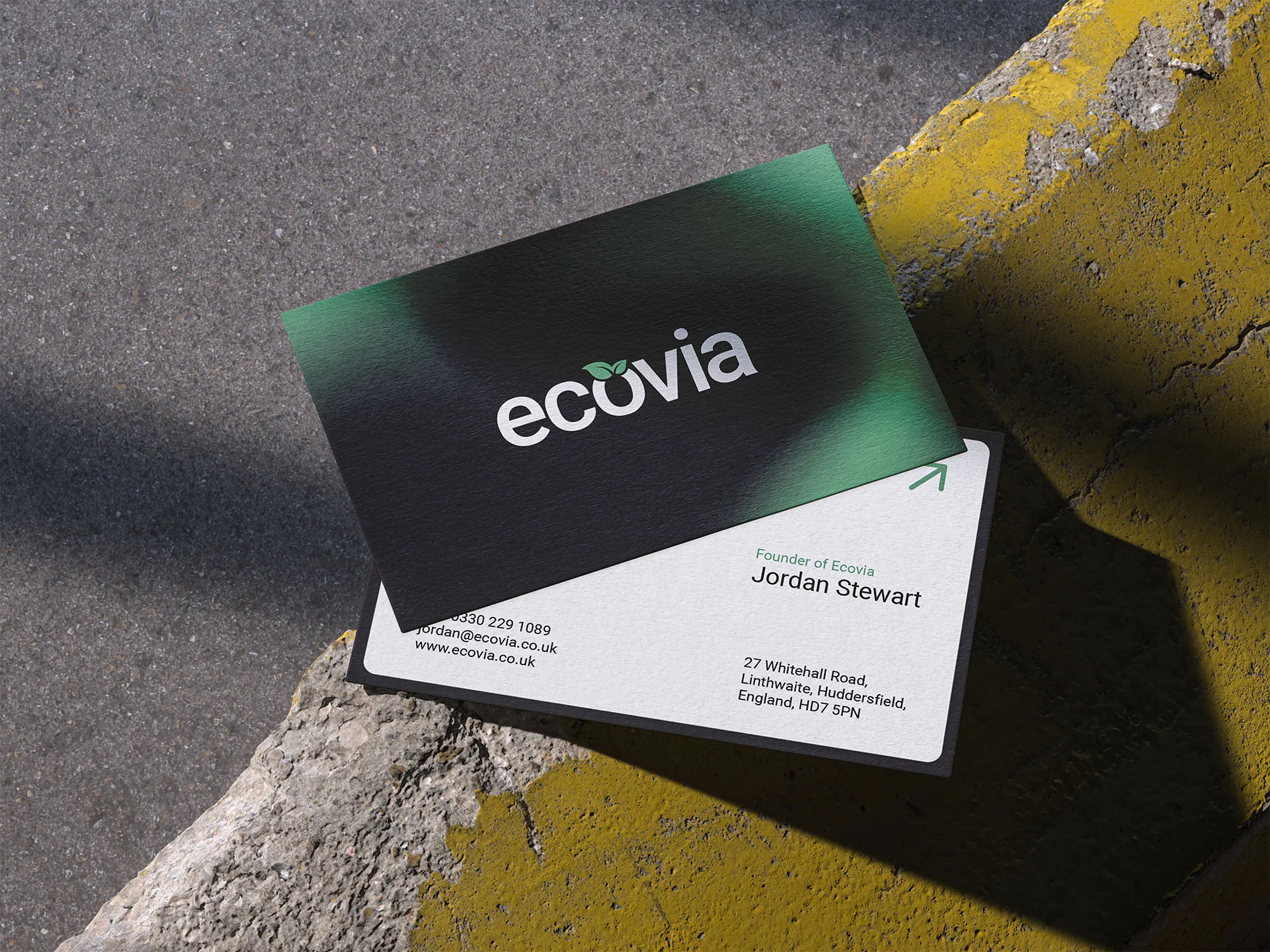 Green-and-white Ecovia business cards displayed on a sunlit concrete step.