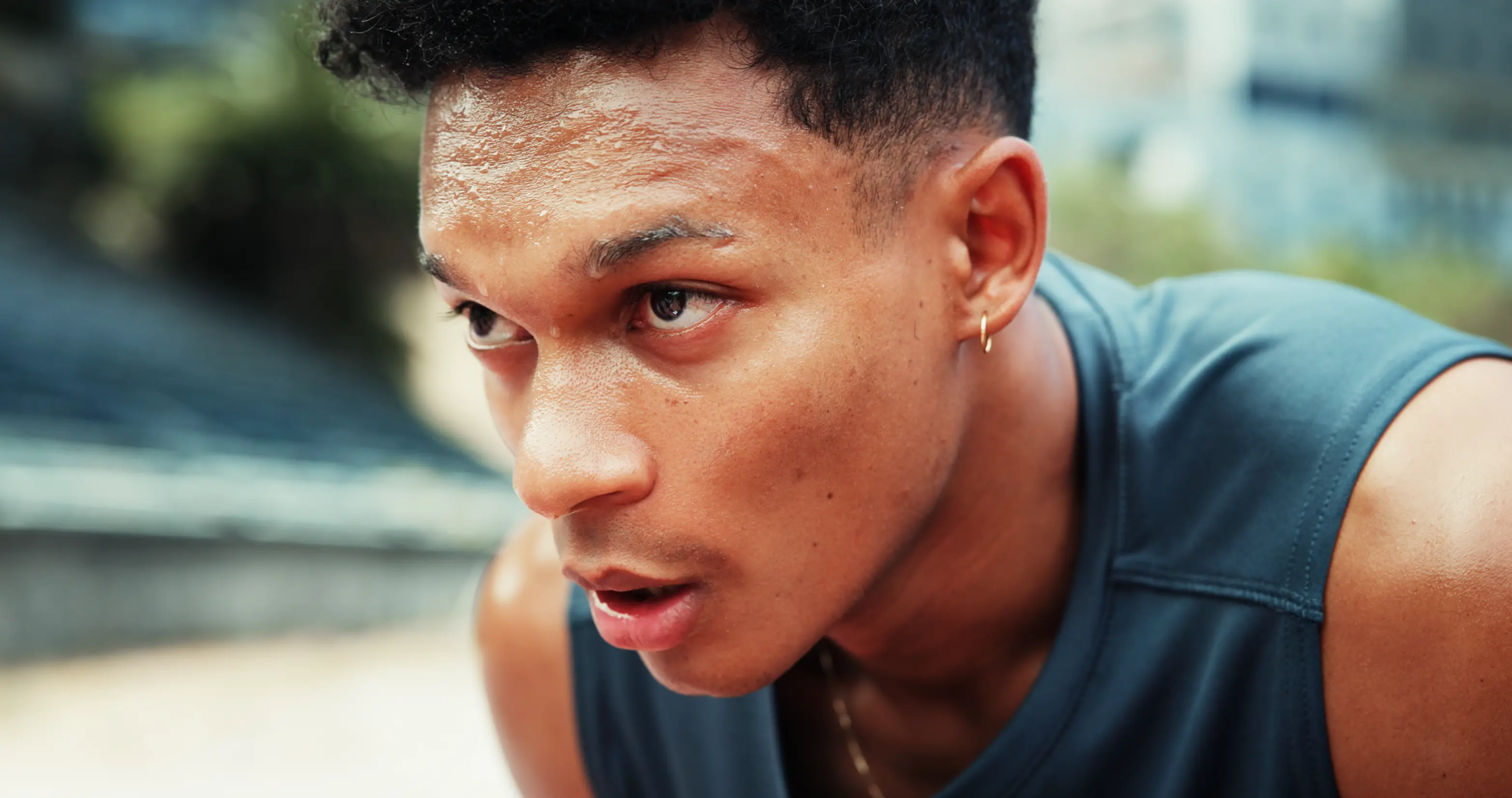 Close-up of a young man sweating and catching his breath during outdoor exercise.
