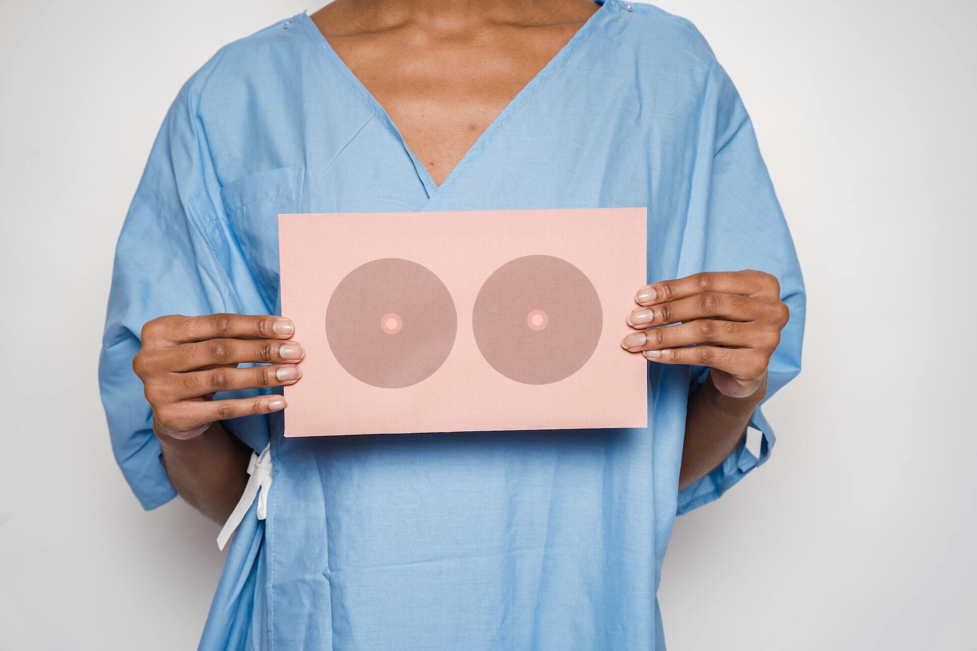 Female patient holding a paper up in front of her that looks like breasts
