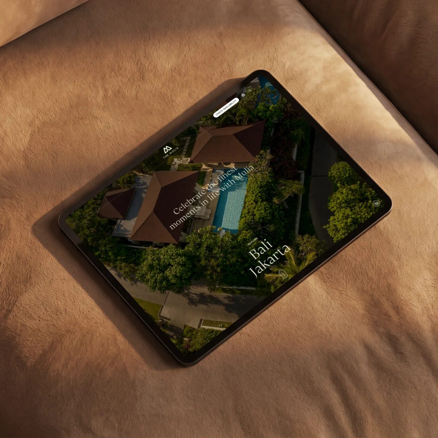 The Mulia website on an iPad resting on a leather sofa