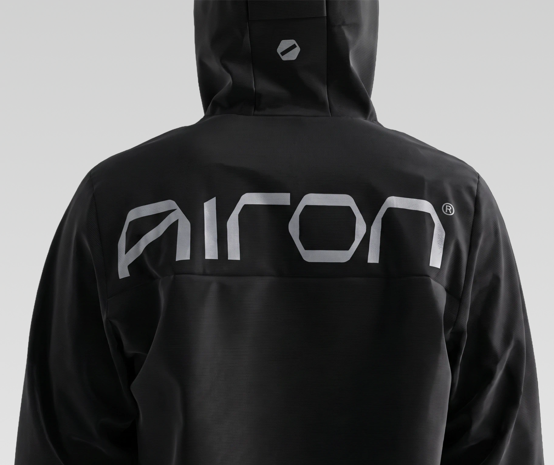 Black hooded jacket with the Airon wordmark printed in reflective grey across the back.