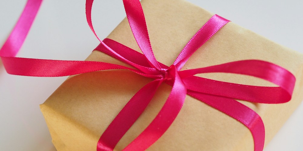 Gift box wrapped in brown paper with a pink ribbon bow