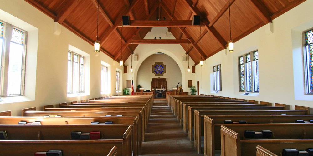 Empty church sanctuary with wooden pews and tall windows