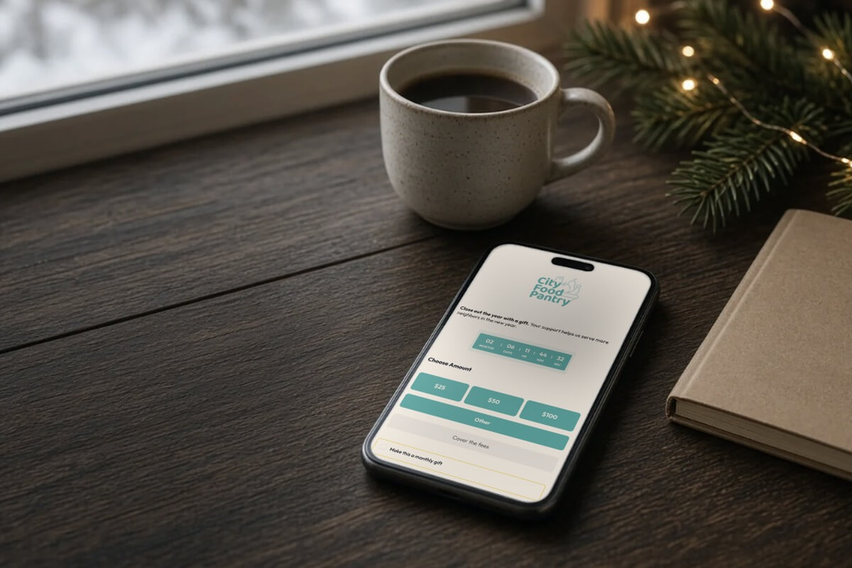 Smartphone showing a simple donation form on a desk by a snowy window, with a coffee mug and evergreen lights