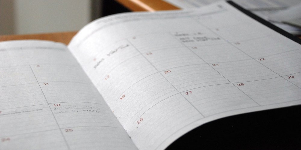 Open monthly planner lying on a wooden desk