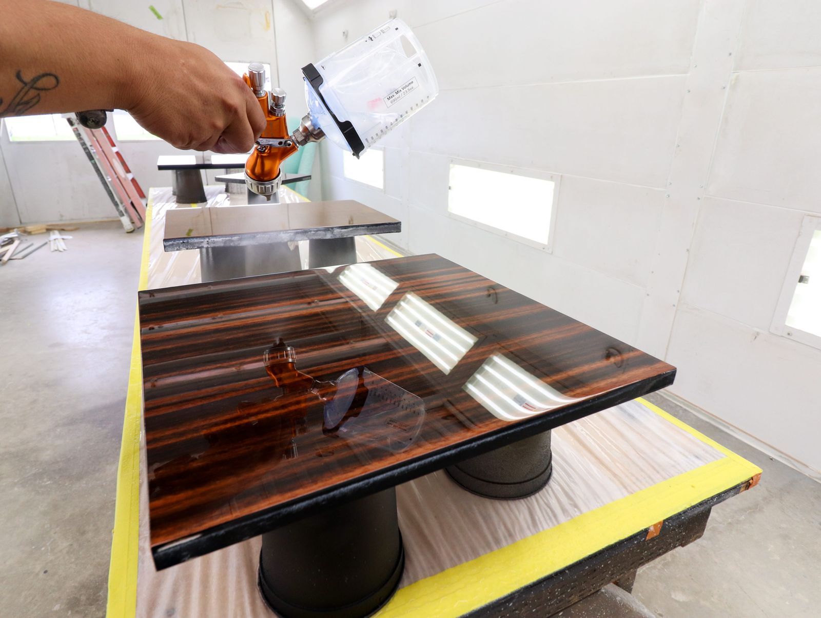 Hand-spraying lacquer on veneer tabletop in the finish room
