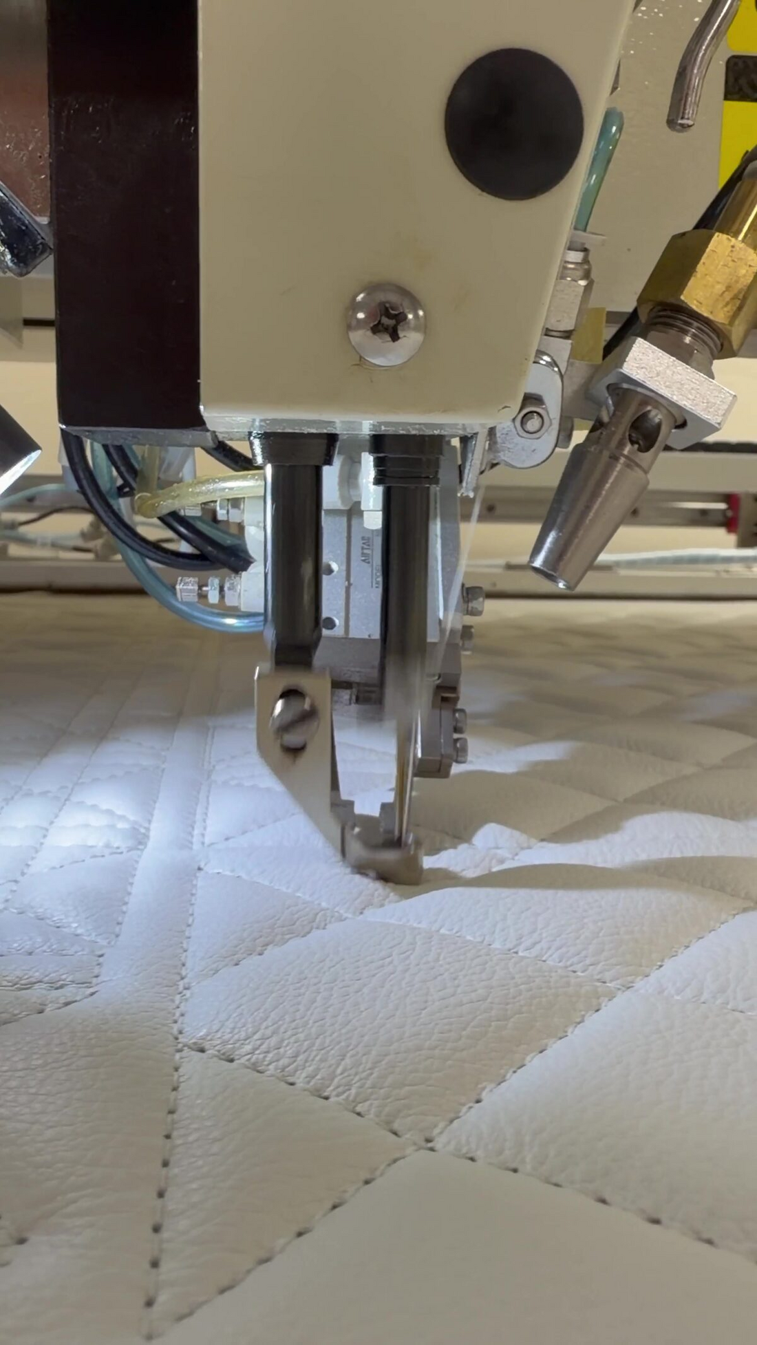 CNC quilting head stitching a diamond pattern into FAA-approved leather