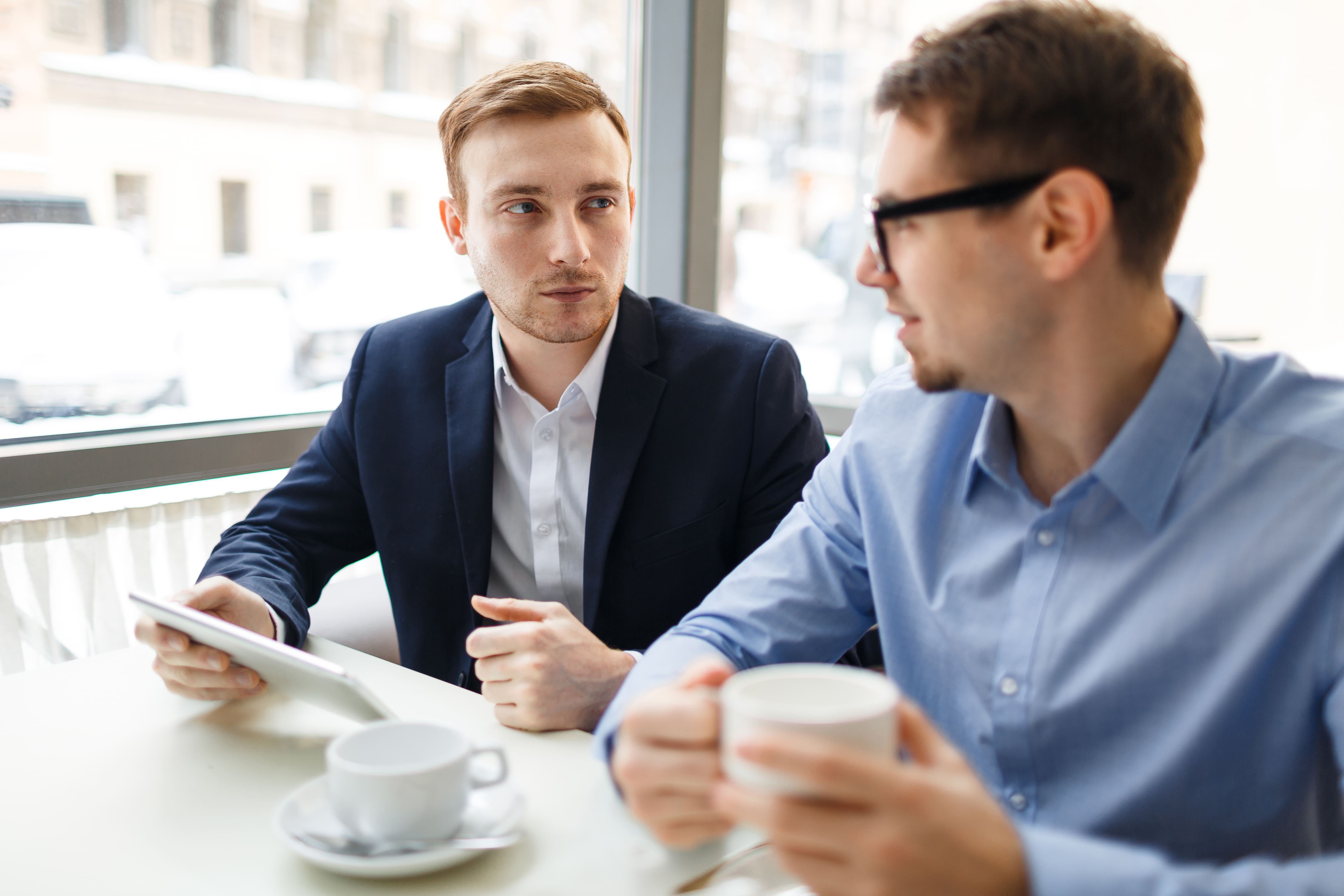 Deux professionnels en rendez-vous d'affaires utilisant Praiz pour capturer les insights de leur échange grâce à l'intelligence conversationnelle et l'automatisation CRM